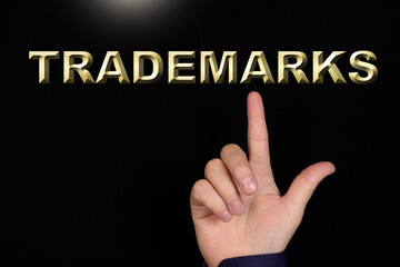 TRADEMARKS text, a word written on a black background pointed to by a hand with the index finger of...
