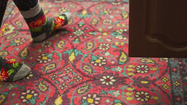 legs in colorful ornate warm wool socks on old ornate red carpet.