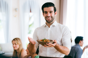 Waitress man serving food to group of diverse customer in restaurant, eatery client woman and man having smile and happy with service mind from cafes staff, lunch or dinner time lifestyle with family - 756266859