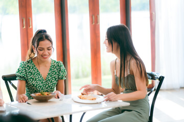 Waitress man serving food to group of diverse customer in restaurant, eatery client woman and man having smile and happy with service mind from cafes staff, lunch or dinner time lifestyle with family