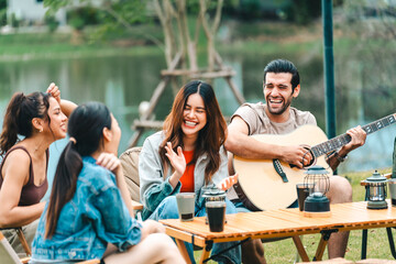 A group of people are sitting around a table with a guitar and a fire pit