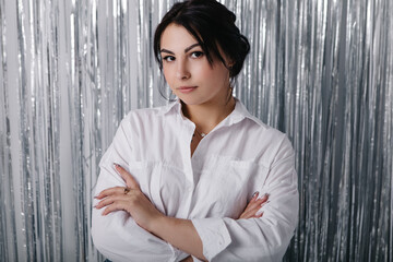 Beautiful pretty woman poses near silver foil glitter tinsel curtain. Shimmer fringe holiday...