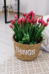 Vertical photo bouquet of pink tulips flowers in vase in bedroom near bed. Spring home decorations interior. International Women`s Day holiday, 8th March concept
