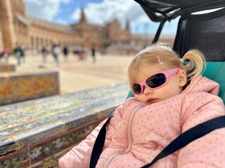 Enfant de 2 ans et demi dormant dans sa poussette avec des lunettes de soleil en Espagne à Séville