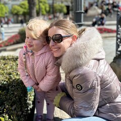 Enfant de 2 ans et demi vêtue d'une veste rose faisant des bulles avec sa maman dans ses bras
