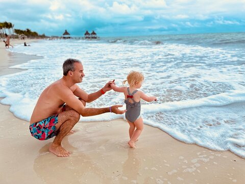 Papa et sa fille de 2 ans et demi sur la plage devant la mer des caraïbes