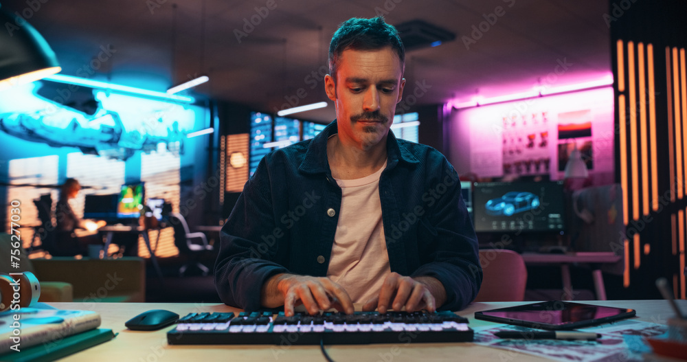 Aufkleber Portrait of a Young Man Typing on Keyboard and Working on Desktop Computer in a Creative Office with Neon Lights. Male Software Developer Writing Code. Point of View of Screen Monitor 