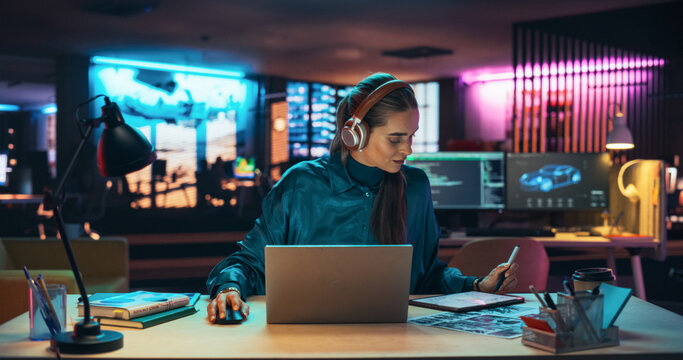 Beautiful Female Specialist is Writing Business Strategy, Using Digital Tablet to Take Notes in Creative Office Environment. Young Project Manager with Headphones Working on Laptop Computer 