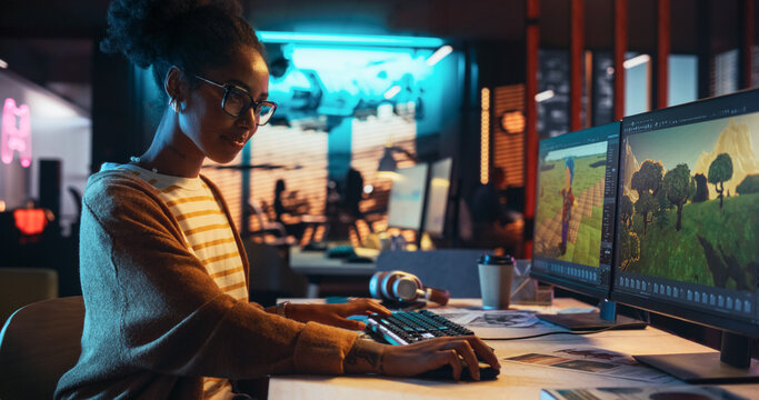 Portrait of Female Video Game Designer Working on a New 3D Level on Desktop Computer in Creative Office. Black Focused Woman Creating Metaverse and Adding Details to a Game Environment 