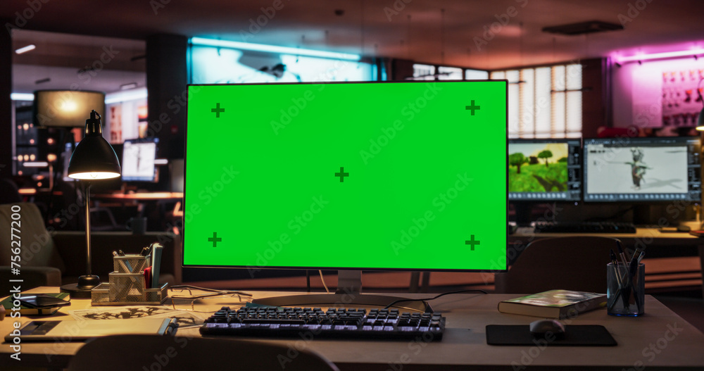 Poster Desktop Computer Monitor Standing on a Wooden Desk with a Green Screen Chromakey Mock Up Display. Creative Office Working Station for Game Developer in Creative Agency