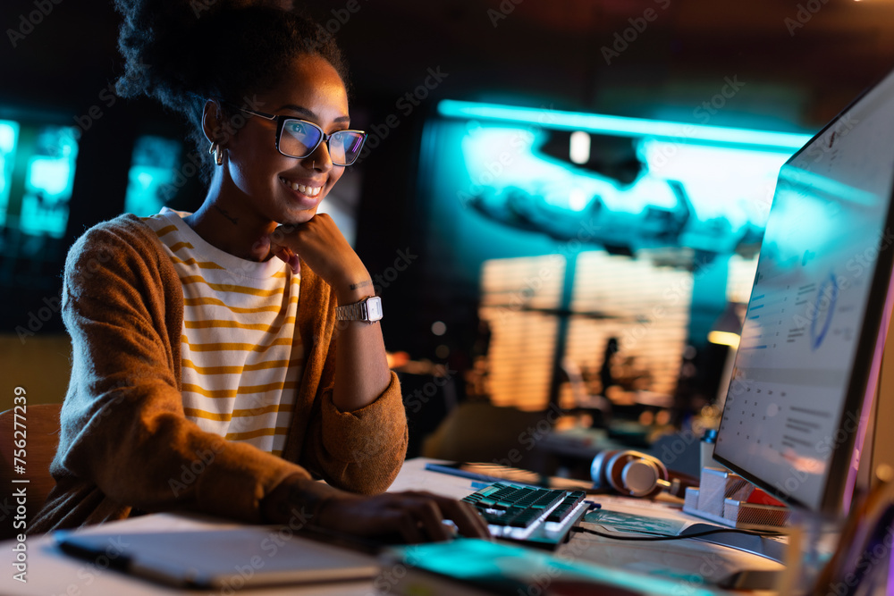 Poster african american female smiling while checking data and statistic charts using desktop computer. por