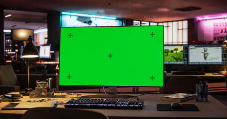 Desktop Computer Monitor Standing on a Wooden Desk with a Green Screen Chromakey Mock Up Display....