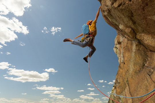 A man is climbing a rock wall with a blue backpack