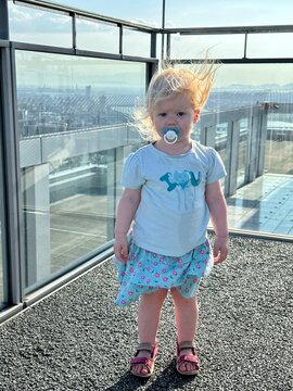 Enfant fille de 1 an et demi avec une tétine en haut d'un building