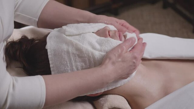 Massage therapist blotting a girl's face with a towel after a massage in a spa