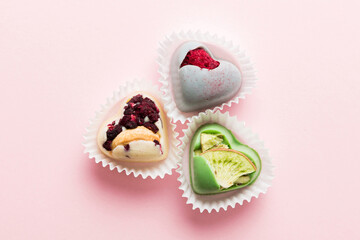 chocolate sweets in the form of a heart with fruits and nuts on a colored background. top view with space for text, holiday concept