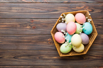 Happy Easter composition. Easter eggs in basket on colored table with gypsophila. Natural dyed colorful eggs background top view with copy space