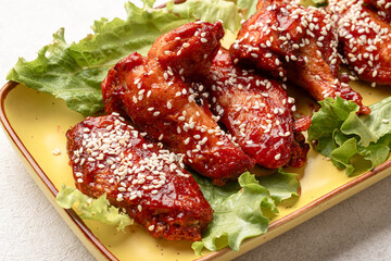 Portion of cooked chicken wings in sauce and sesame seeds