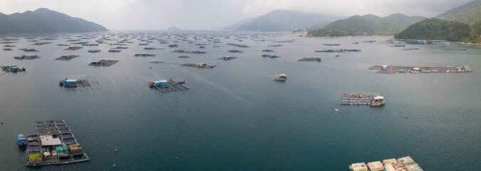 Panoramic aerial drone shot of floating aquaculture fish farm village in Vung Ro Bay on Vietnam's South China Sea coast