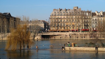 Inondation des quais de la ville de Paris, le fleuve de la Seine en crue en février 2018, avec des piétons au bord de l’eau, sur la pointe du square du Vert-Galant inondée, île de la Cité (France)