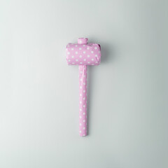 Vintage hammer packaged in pink polka dot gift paper on a blue background, top view.