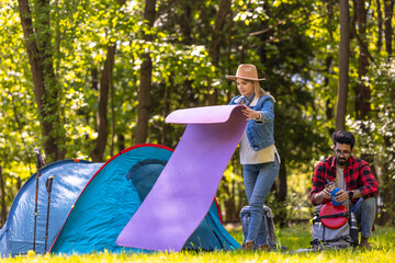 Woman in a straw hat rolling a mat near the tent © zinkevych