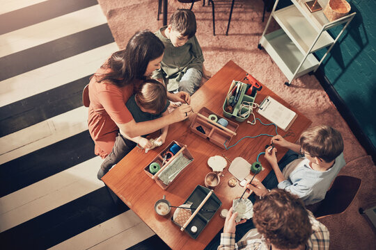 High angle view of a loving mother, father and their young sons doing a family arts and crafts class together at the weekend