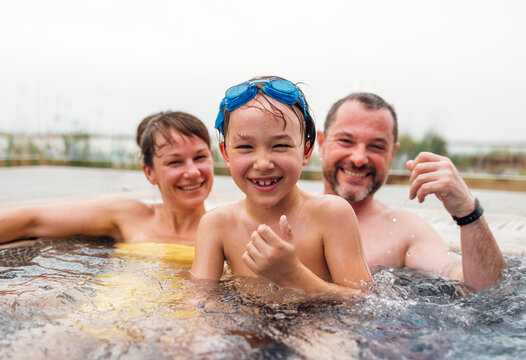 Cute boy and his parents are swimming in a Jacuzzi and an open-air pool.