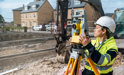 Close-up portrait of a woman site engineer surveyor working with theodolite total station EDM...