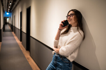 Flirting delighted woman talking on mobile phone in hotel corridor flirting