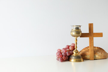 Bread, cup, grapes and wooden cross on white background, space for text