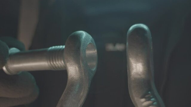 Worker checkups bolt for metal hinge fixation in plant workshop closeup. Iron parts fastening with screw pin at factory. Mechanism details