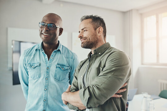 Two diverse businessmen smiling while working in the boardroom of an office
