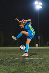 Obraz na płótnie Canvas young girl wearing a blue uniform playing with a ball at an evening practice, athlete kids concept. High quality photo