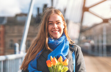 Portrait of happy woman with tulips  having a fun day, walking around an English city Lifestyle, tourism,  world woman's day concept - obrazy, fototapety, plakaty