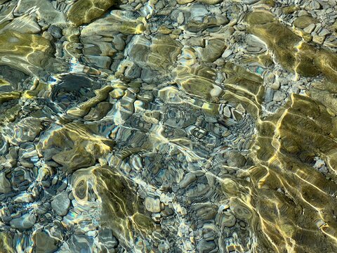 Sea underwater stones pebbles on the seabed in clear transparent water.