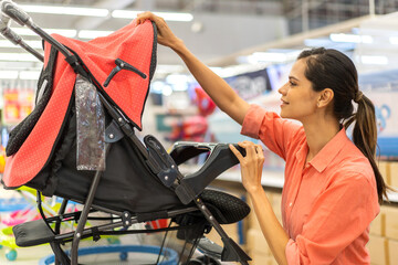 Mother woman carefully examines a modern, decision making stroller in spacious baby store, mindful parent, seeking quality and safety in children products family planning, baby care products, shopping
