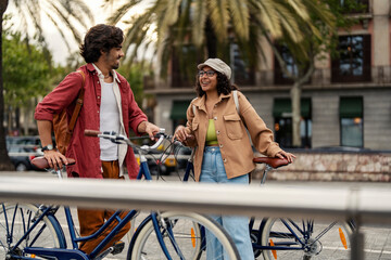 Happy trendy friends with bikes standing on the street and chatting.