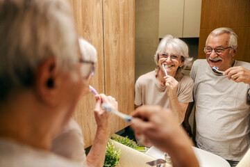 A happy senior couple is brushing teeth in the morning.