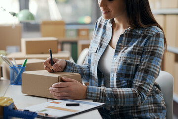 Woman writing a shipping address on a delivery box