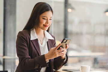 Beautiful young millennial Asian woman using a smartphone at a cafe. Portrait of a gorgeous smiling...