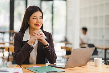 Portrait of professional millennial Asian businesswoman in casual attire analyzing financial data on her laptop computer in the office.