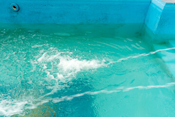 The spray water jet fills the pool with clean water . Cleaning process of pool cleaning....