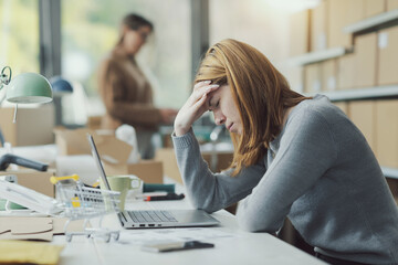 Exhausted woman with headache in the office