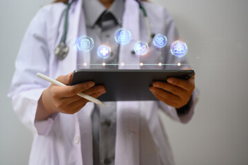 Female doctor in a white coat using digital tablet with virtual displays medical information icons