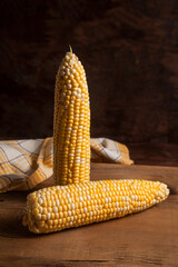 Two cobs sweet corn on wooden background..