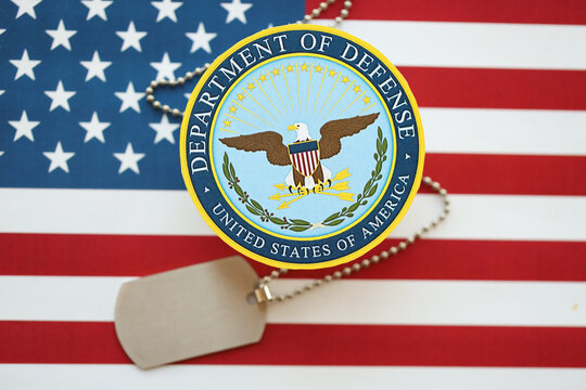 KYIV, UKRAINE - MARCH 9, 2024 US Department of Defense seal with dogtags on United States of America flag close up