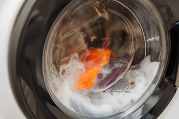 Closeup of washing machine door with spinning laundry