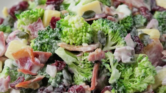 Healthy Homemade Broccoli Salad with bacon, red onion, cranberries, pumpkin seeds and cheese. Rotating video