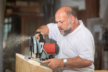 Tischler in seiner Werkstatt arbeitet mit Handkreissäge - 756349215